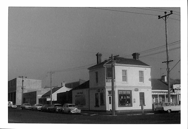 Two storey building on a street corner with a shop on the ground floor.