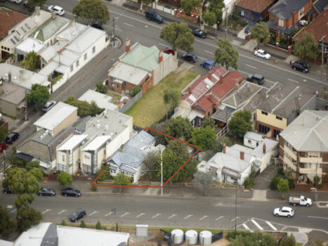 An aerial image of a triangular shape piece of land bordered by two streets. Quite a number of houses are shown in the image with one particular piece of land outlined in red. All houses shown are different in sizing, roofing materials. Some have gardens so don't.