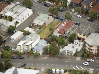 An aerial image of a triangular shape piece of land bordered by two streets. Quite a number of houses are shown in the image with one particular piece of land outlined in red. All houses shown are different in sizing, roofing materials. Some have gardens so don't.