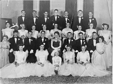 Group of men in black suits and bow ties and women in white dresses.