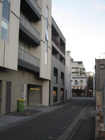 New style of low rise appartments built in Port Melbourne. All apartments have a balcony with underground parking. This one is able of creme and grey colouring . In the foreground there is another low rise apartment block with retail shops below. 