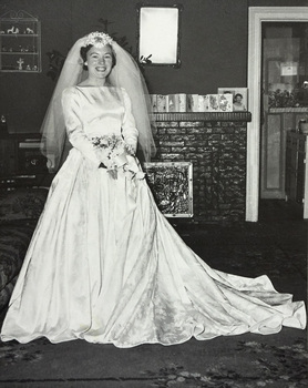 A women in her wedding dress standing in front of a fireplace.