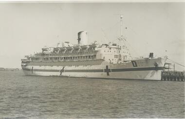 Photo shows a side view of the hospital ship "Oranje" berthed at Princes Pier. The ship has large crosses painted on her sides identifying her as a hospital ship.