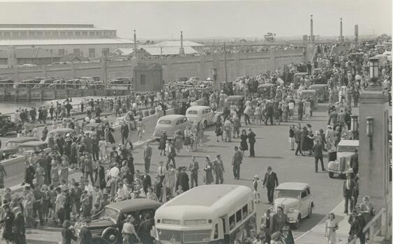 Photo shows crowds at Station Pier to see the return of "Oranje", a ship which was returning soldiers from World War 11. You can see the old Centenary bridge and the stairway that led down onto Station Pier.  There various old cars and an old transport bus shown in the photo as well.