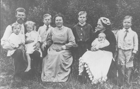 Macdonald family group consisting of a man, two women and six children posing outdoors.