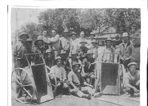 Large group of men in work clothes posing for camera