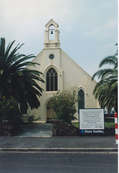 The front facade and gardens of a church with a central bell tower.
