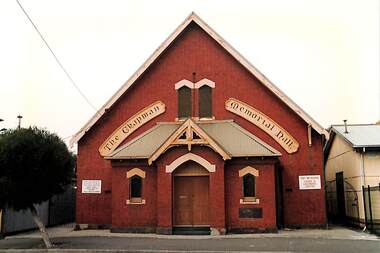 Small red brick building with steep roof called The Chapman Memorial Hall.