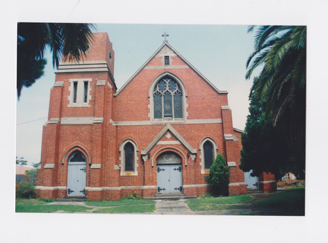 The front of a red brick church with a square tower on the left.