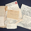 An unorganised pile of notes and letters of varying sizes. Some are small scraps of paper, some are envelopes and two are full letters. Most of the details are handwritten but one of the letters is typed.