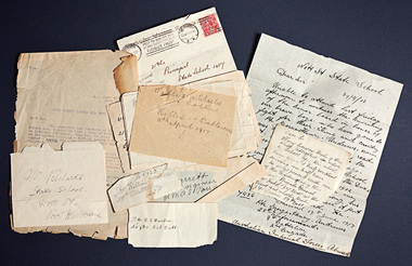 An unorganised pile of notes and letters of varying sizes. Some are small scraps of paper, some are envelopes and two are full letters. Most of the details are handwritten but one of the letters is typed.