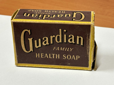 Brown and yellow rectangular cardboard box with text "Guardian Family Health Soap"