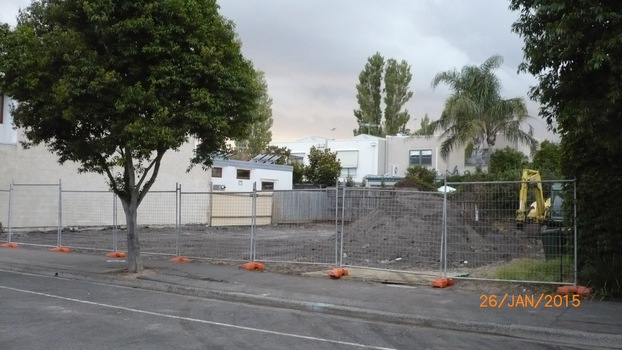 1. Block of land after building has been demolished, small digger can be seen on the right side of photo, security fencing along front of block.  2. same block of land photo taken at a different angle. 