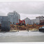Demolition site of a large building, photo shows digger at work with a security wire fence at the front of the site. 