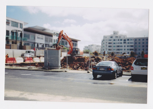 Demolition site of large building showing digger and other machinery at work.