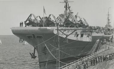 Photo shows the stern of the British aircraft carrier HMS Glory at Station Pier, Jan 1946. You can also see the aircraft that were used on this ship and the crowds lining up to inspect this ship.