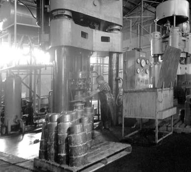 Interior of factory with a man working at a large machine.