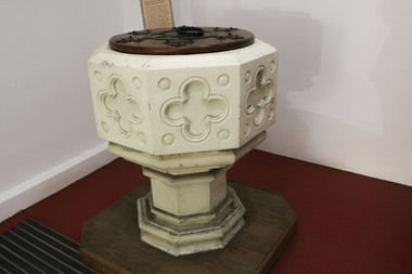 Large white free-standing baptismal font with a wooden cover.