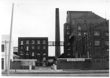Multi-storey factory complex including a tall free-standing brick chimney.