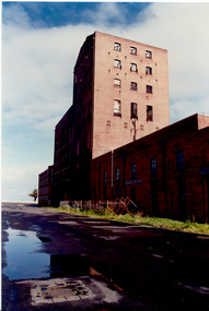 Derelict multi-storey red brick factory building.
