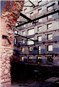 Interior of a derelict multi-story red brick factory building.