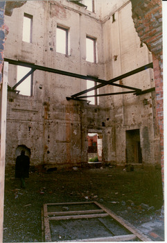 Interior of a derelict multi-story red brick factory building.
