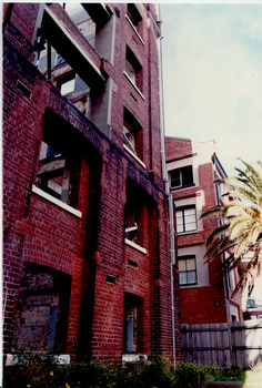 Exterior of multi-storey red brick derelict factory building.