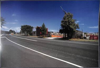 Partly demolished buildings viewed from across an empty road.