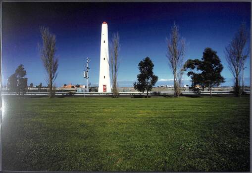 Looking across a grassed area to a white lighthouse-like structure.