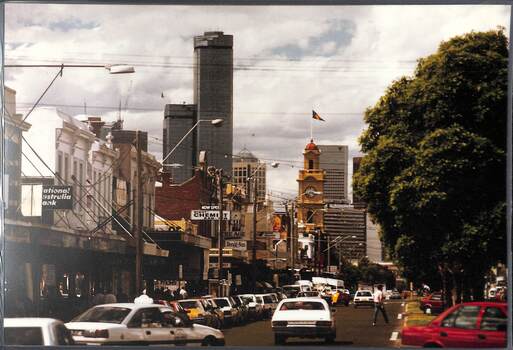 View of a busy commercial street with a few skyscrapers in the far distance.