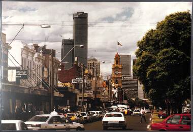View of a busy commercial street with a few skyscrapers in the far distance.
