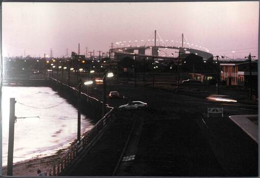 Nightime view across the seafront with a large road bridge in the background.