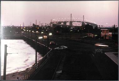 Nightime view across the seafront with a large road bridge in the background.