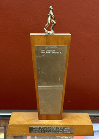 Wooden trophy with a small gold-coloured figure of a runner on top and a panel for past winners with two names.