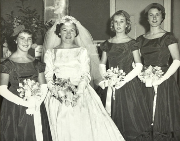 A bride in wedding dress posing with her three bridesmaids.