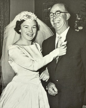 A bride posing arm in arm with a man in a suit.