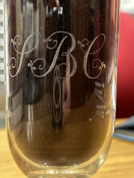 The letters S B and C engraved in a cursive style on the bowl of a drinking glass