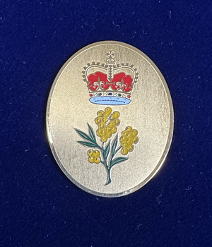 Gold-coloured oval bearing a crown and sprig of wattle