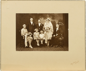 Studio portrait of wedding party mounted on cardboard.