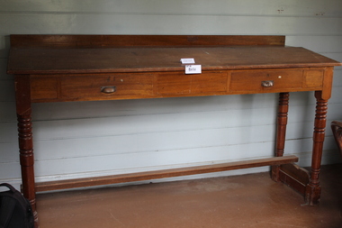 A timber table with turned legs and drawers installed unter the tabletop