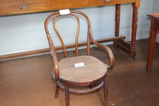 Antique wooden chair with curved back and upholstered seat. 