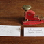 small red metal stapler with large round button on top