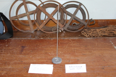 Metal skewer rising vertically from paperweight. 