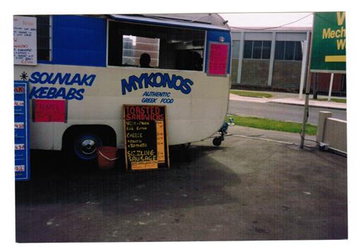 A photograph of a food vendor's van parked in a street. 