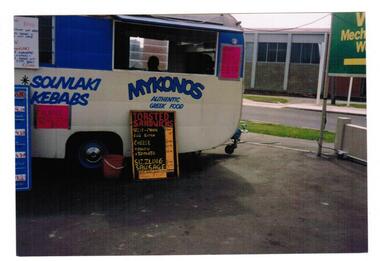A photograph of a food vendor's van parked in a street. 