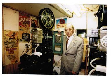A man standing beside a fim projector.