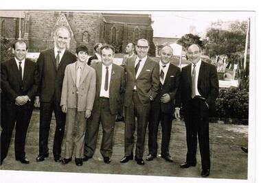 Six men and a young boy are standing outside a church.
