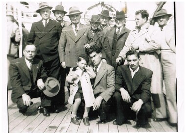 Eleven men and a boy on the deck of a ship.