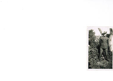Australian soldier standing next to shrubbery.