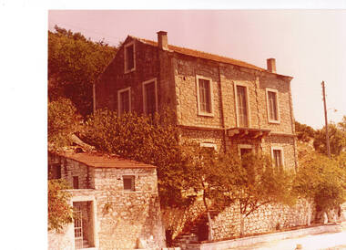 A stone house fronting onto a roadway.